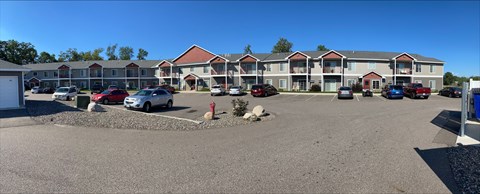 A parking lot in front of a building with several cars parked.