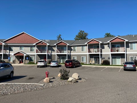 A parking lot in front of a building with cars parked.