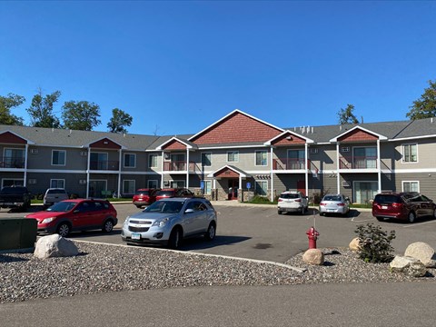 A parking lot in front of a building with cars parked.