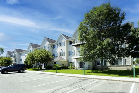 A large white building with a blue car parked in front.