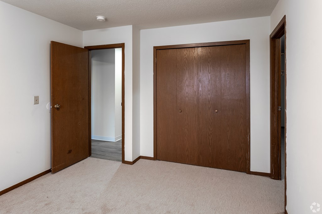 BLDG B/D - A room with two brown doors and a carpeted floor.