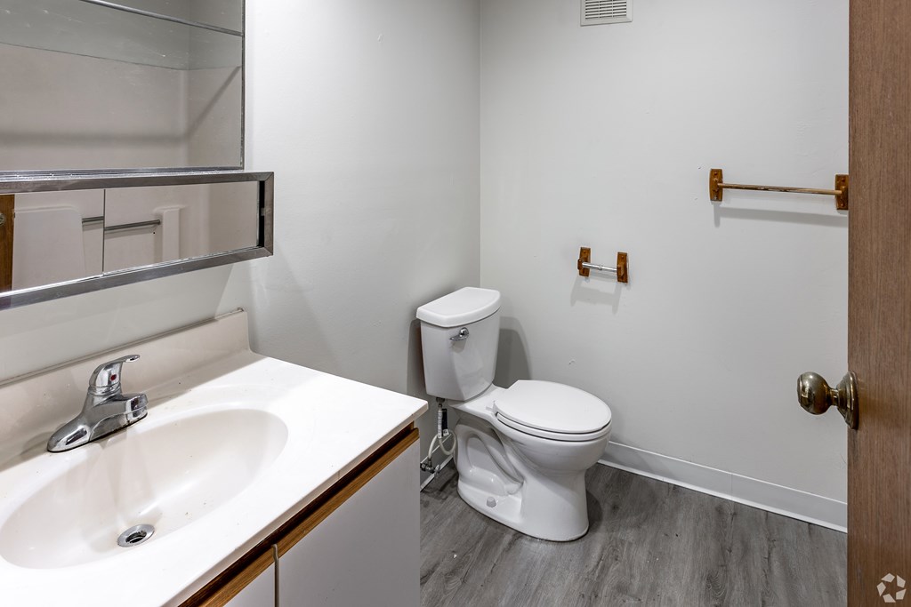 BLDG B/D - A white toilet sits next to a sink in a bathroom.