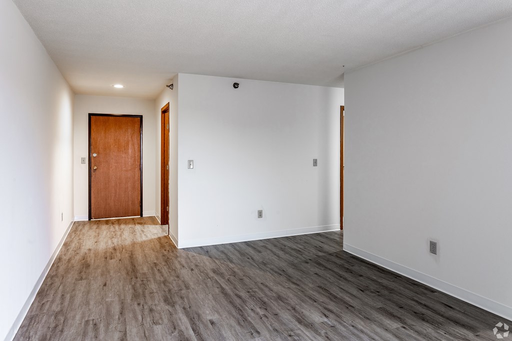 BLDG B/D - A room with a wooden floor and a brown door.