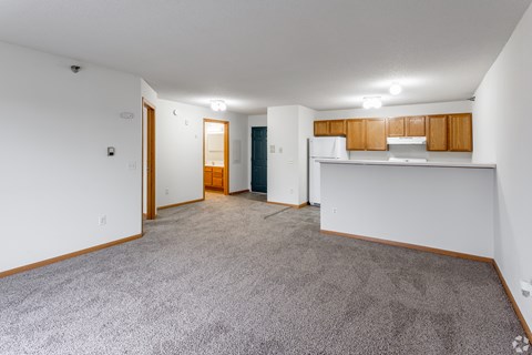 A spacious living room with a carpeted floor and white walls.