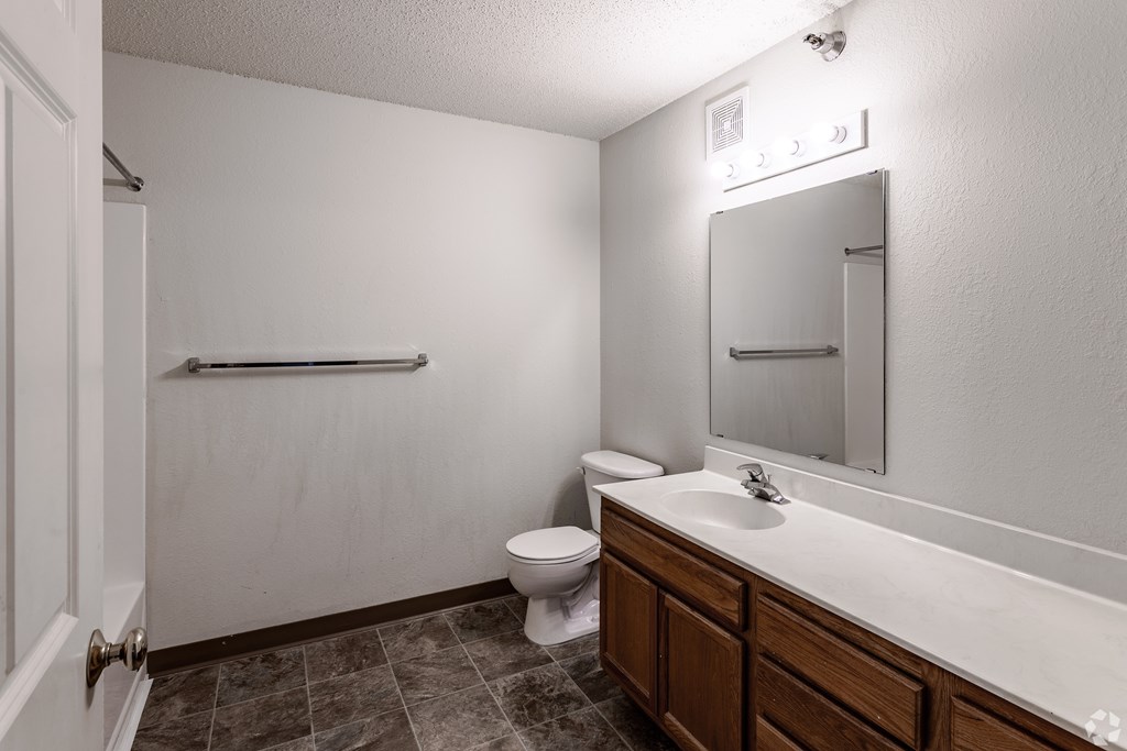 BLDG A/C - A bathroom with a toilet, sink, and mirror.