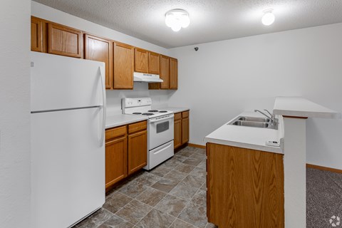 A kitchen with white appliances and wooden cabinets.