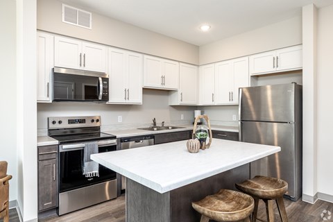 A kitchen with a white counter top and stainless steel appliances.