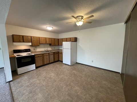 A kitchen with a white refrigerator and wooden cabinets.