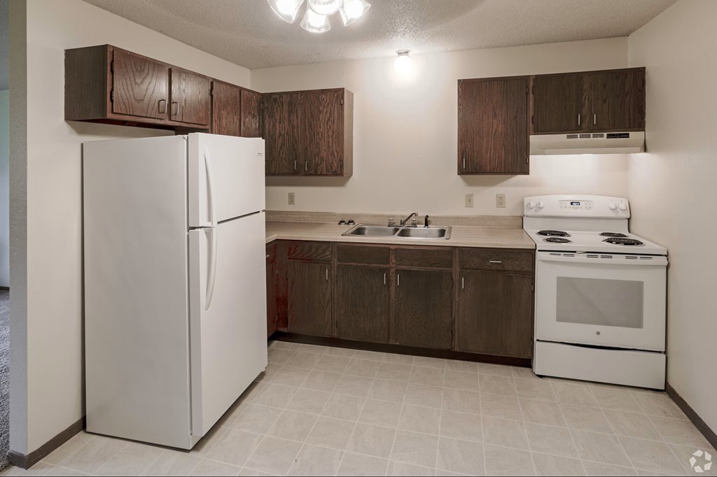 A white refrigerator is in a kitchen with brown cabinets.