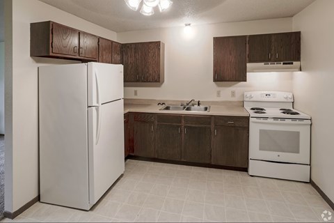 A white refrigerator is in a kitchen with brown cabinets.
