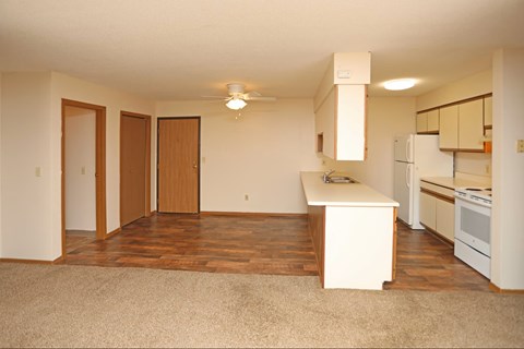 A kitchen with white appliances and wooden floors.