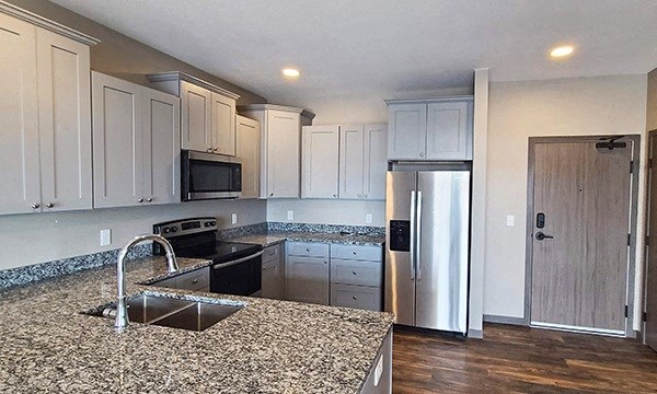 a kitchen with granite counter tops and a stainless steel refrigerator