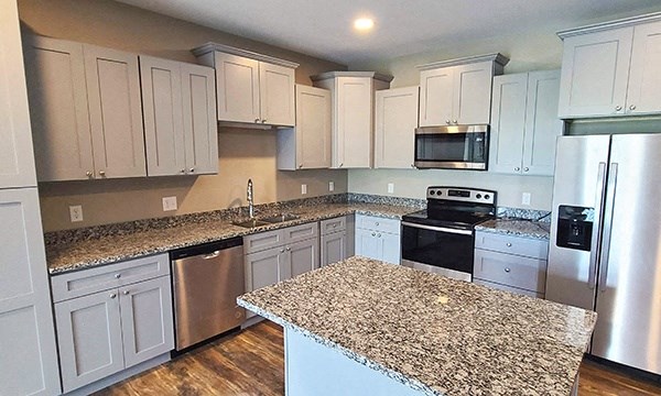 a kitchen with granite counter tops and white cabinets