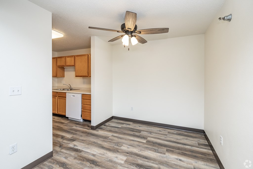 A room with a ceiling fan and a dishwasher in the kitchen area.