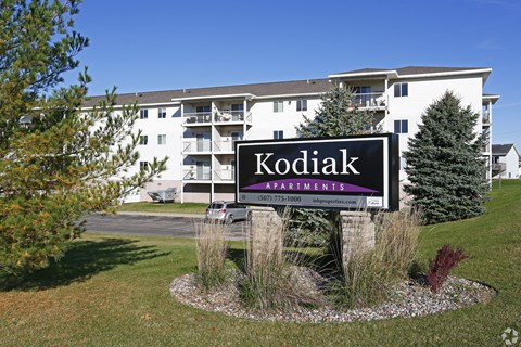 A sign for Kodiak Apartments in front of a building.