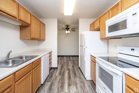 A kitchen with white appliances and wooden cabinets.