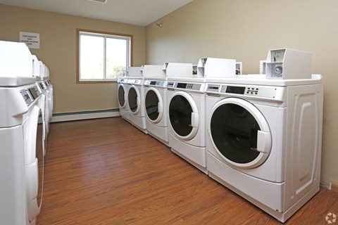 A row of white front load washing machines in a laundromat.