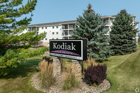 A sign for Kodiak Apartments is in front of a building.