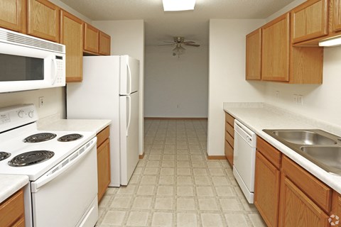 A kitchen with white appliances and wooden cabinets.