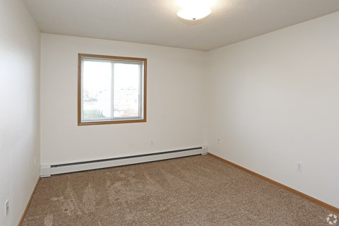 A room with a carpeted floor and a window.