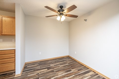 A room with a ceiling fan and wooden flooring.