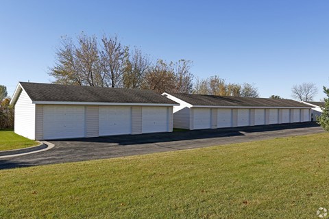 A long white garage with a black roof and a white car parked in front.
