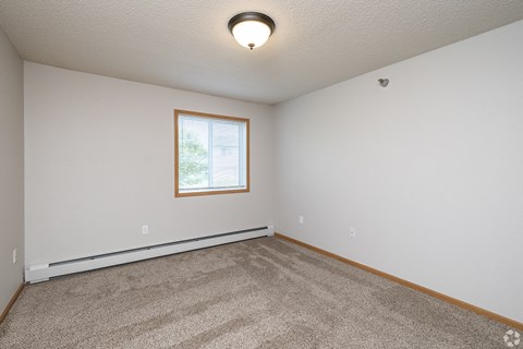 A room with a carpeted floor and a window.