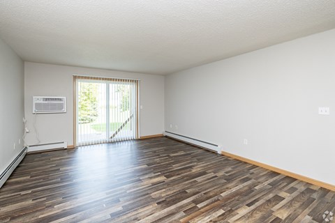A room with wooden flooring and a sliding glass door leading outside.