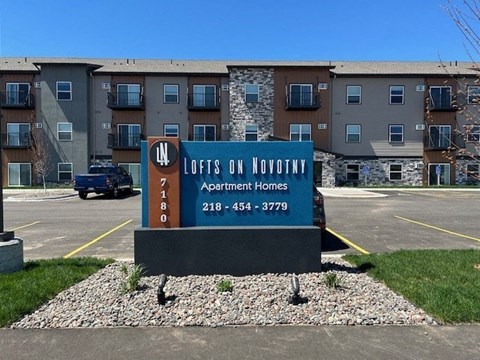 a sign in a parking lot in front of an apartment building