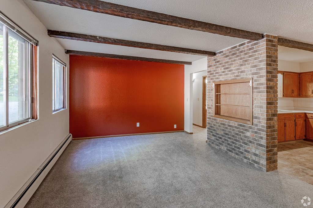A room with a red wall and a fireplace.