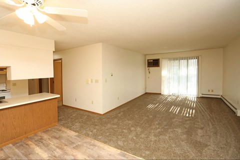 A room with a ceiling fan and a window with curtains.