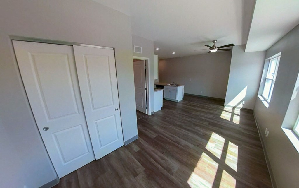 an empty living room with wooden floors and a ceiling fan