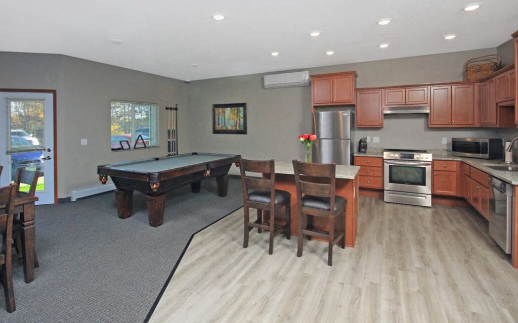 a living room with a pool table and a kitchen