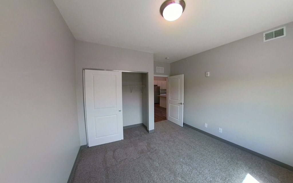 a bedroom with a carpeted floor and a door to a closet