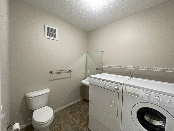 a laundry room with a toilet and a washing machine