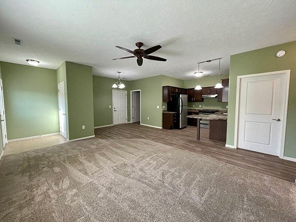 an empty living room and kitchen with a ceiling fan
