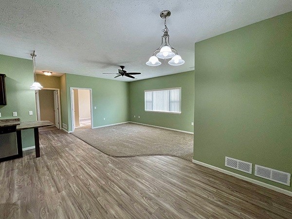 an empty living room with green walls and a ceiling fan