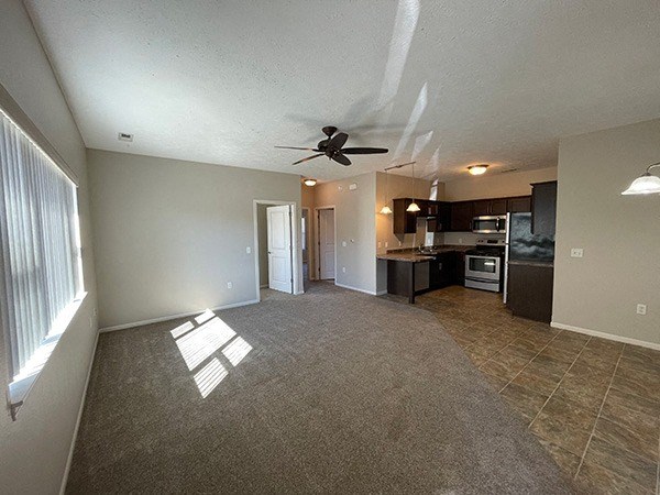 an empty living room and kitchen with a ceiling fan