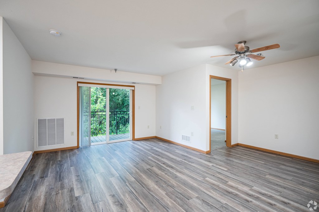 A room with a ceiling fan and sliding glass doors.