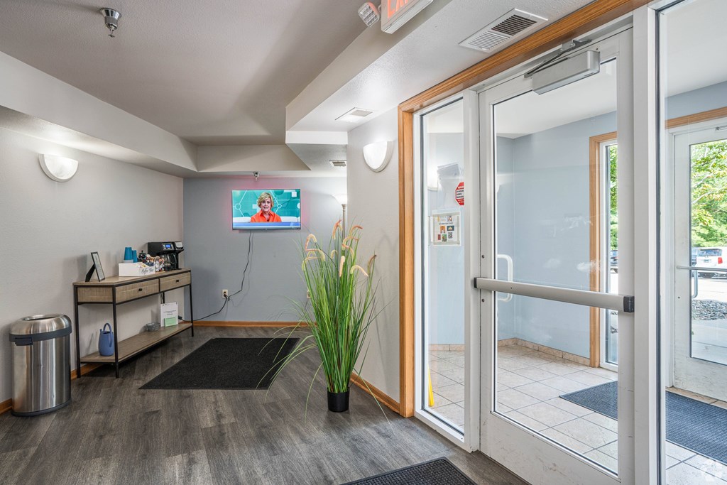 A room with a TV on the wall and a plant in a vase.