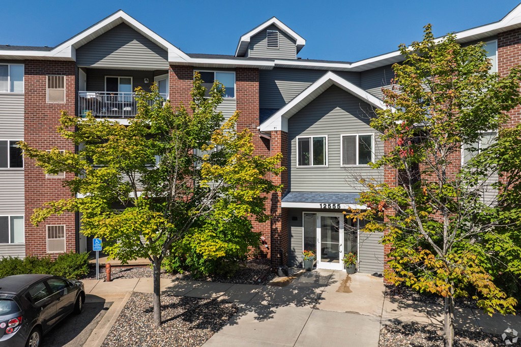 A multi-story apartment building with a car parked in front.