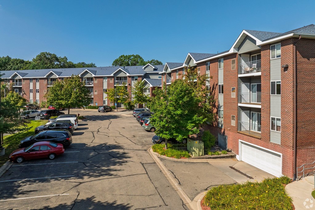 A sunny day at a residential area with apartment buildings and cars parked in the driveways.