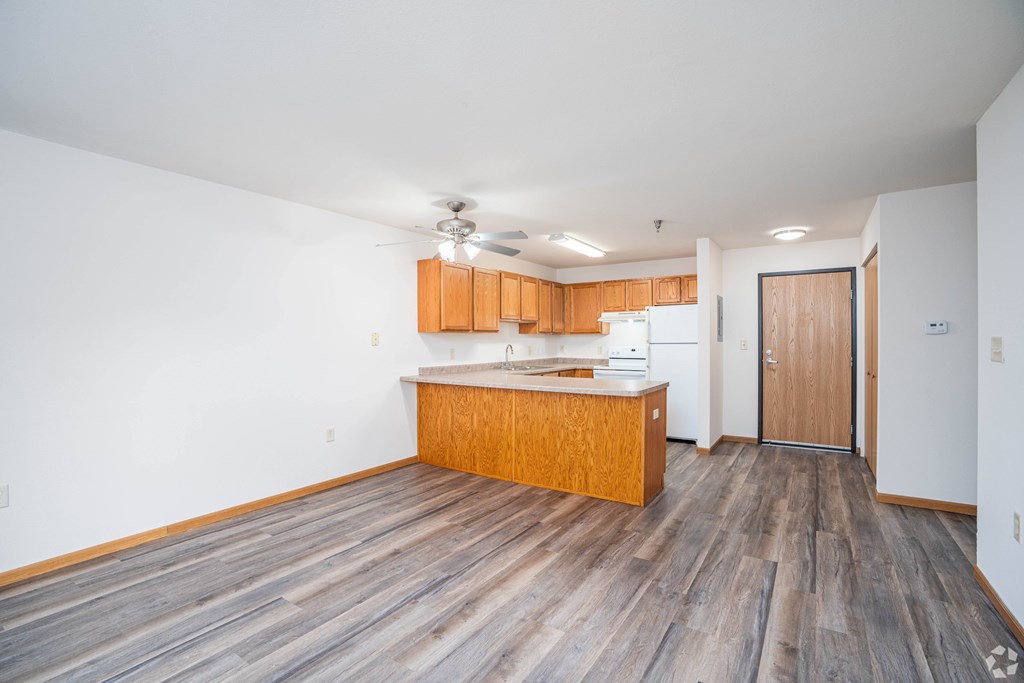 A kitchen with wooden floors and a ceiling fan.