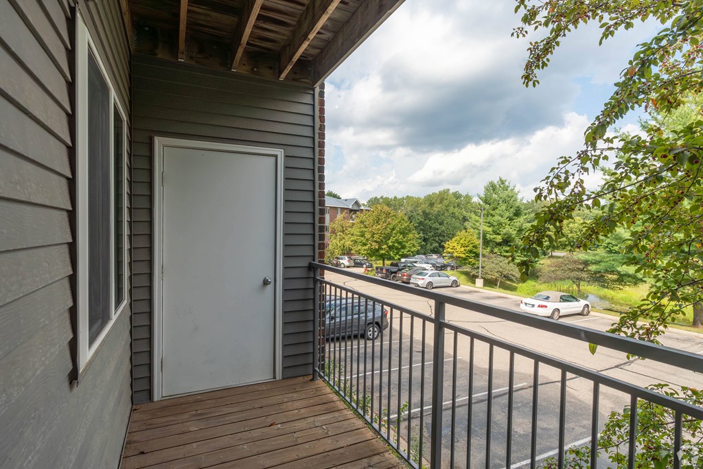 A balcony with a white door and a view of the street below.