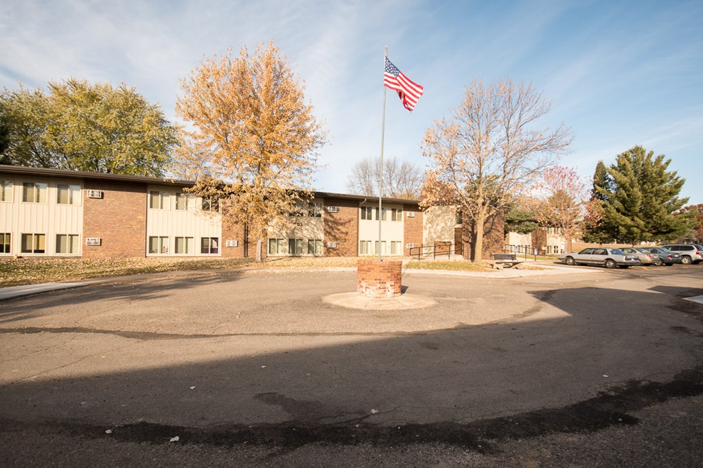 A flag on a pole stands in front of a building.