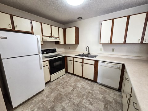 A kitchen with white appliances and wooden cabinets.
