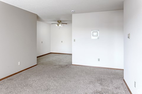 A room with a carpeted floor and a ceiling fan.