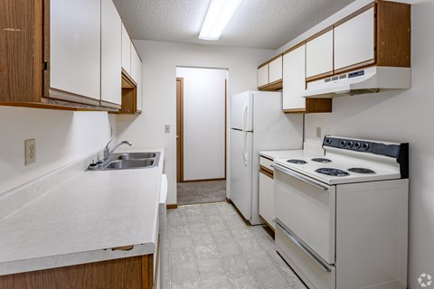 A kitchen with white appliances and wooden cabinets.