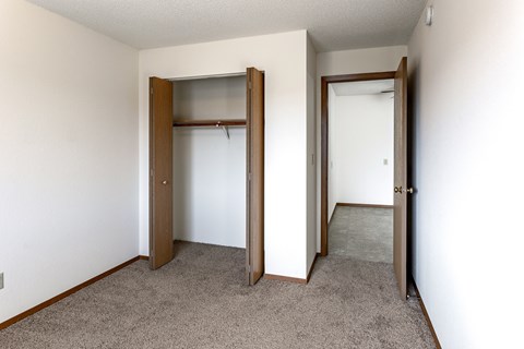 A room with a carpeted floor and two open doors.