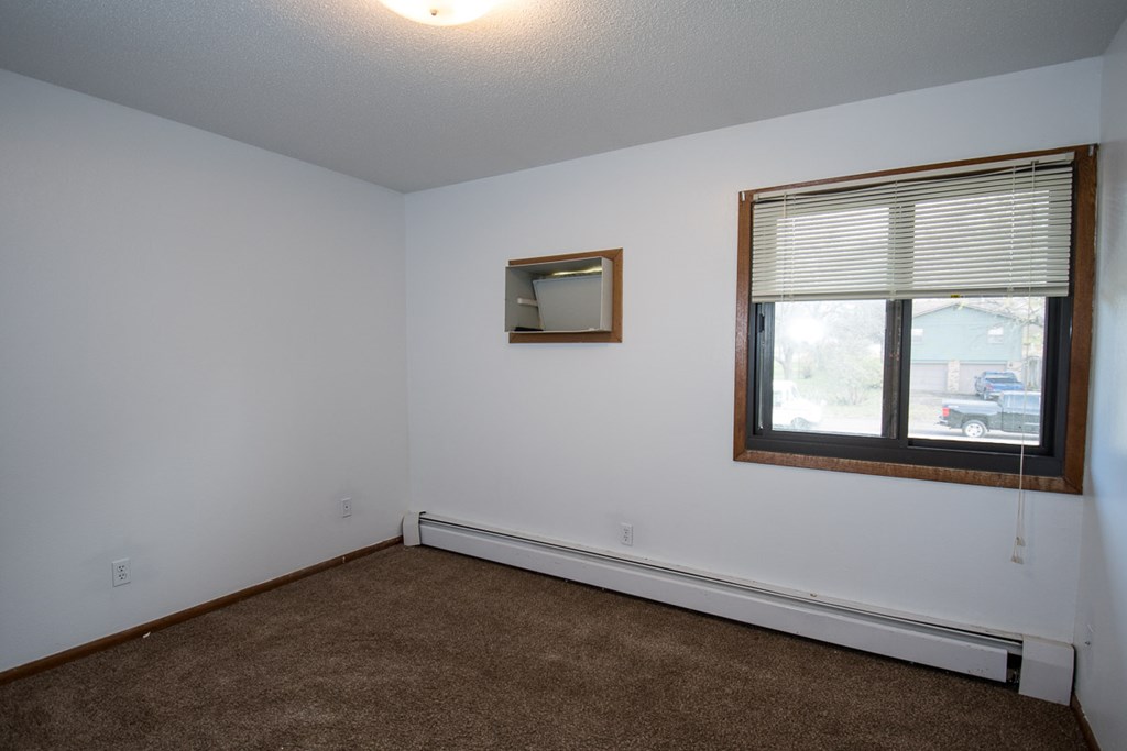 A room with a window and a mirror on the wall.